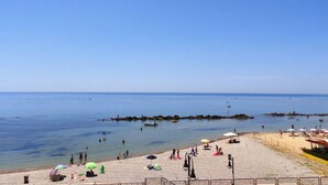 Una platja amb cel blau, aigua tranquil·la i gent gaudint del sol.