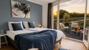 Un dormitorio con una cama grande, vistas al exterior y un balcón con mobiliario.