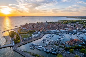 An aerial view of a coastal town with a marina, waterfront buildings, and a prominent church tower.