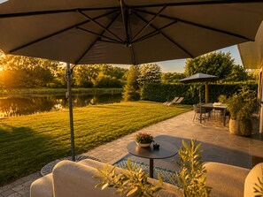 Patio esterno con tavolo, sedie e un ombrellone grande.