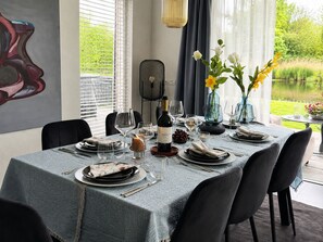 Une table à manger dressée avec des assiettes, des verres et une bouteille de vin, entourée de chaises.