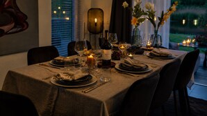 Una mesa de comedor lista para una comida, con copas de vino, platos y velas.