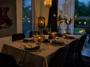 A dining table set for a meal with wine glasses, plates, and candles.