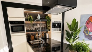Una cocina moderna con encimera negra, armarios blancos y horno integrado.