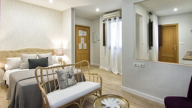 Une chambre à coucher avec un lit, une table de chevet, une lampe et un grand miroir.