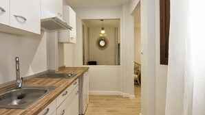 Une cuisine moderne avec des meubles blancs, un plan de travail en bois et un évier en acier inoxydable.