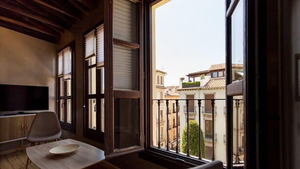 Ein Balkon mit Blick auf Gebäude, einem Tisch und einem Stuhl.