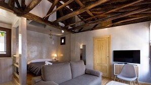 Ein Zimmer mit Holzboden, einem grauen Sofa, einem Fernseher und einem Sessel.