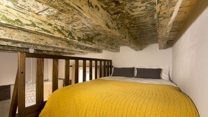 Un dormitorio con techo de madera, una cama con manta amarilla y dos almohadas.
