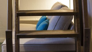 Una escalera de madera apoyada en un sofá con un cojín y una almohada.