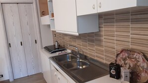 A modern kitchen with a stainless steel sink, white cabinets, and a tiled backsplash.