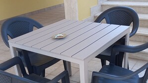 A patio area with a table and chairs, a staircase, and a yellow wall.