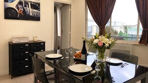 A dining area with a table set for two, a vase with flowers, and a poster on the wall. - L'appartement des Champs Elysées (Paris)