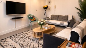 A modern living room with a flat-screen TV, a sofa, a coffee table, and a floor lamp. - L'appartement des Champs Elysées (Paris)