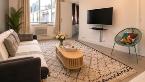 A modern living room with a sofa, coffee table, TV, and a view of the city. - L'appartement des Champs Elysées (Paris)