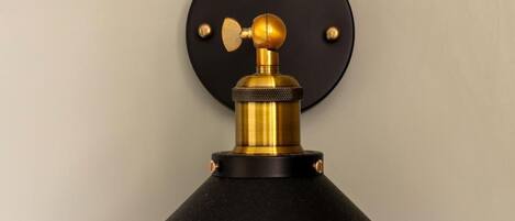 A wall-mounted lamp with a black shade and brass accents.