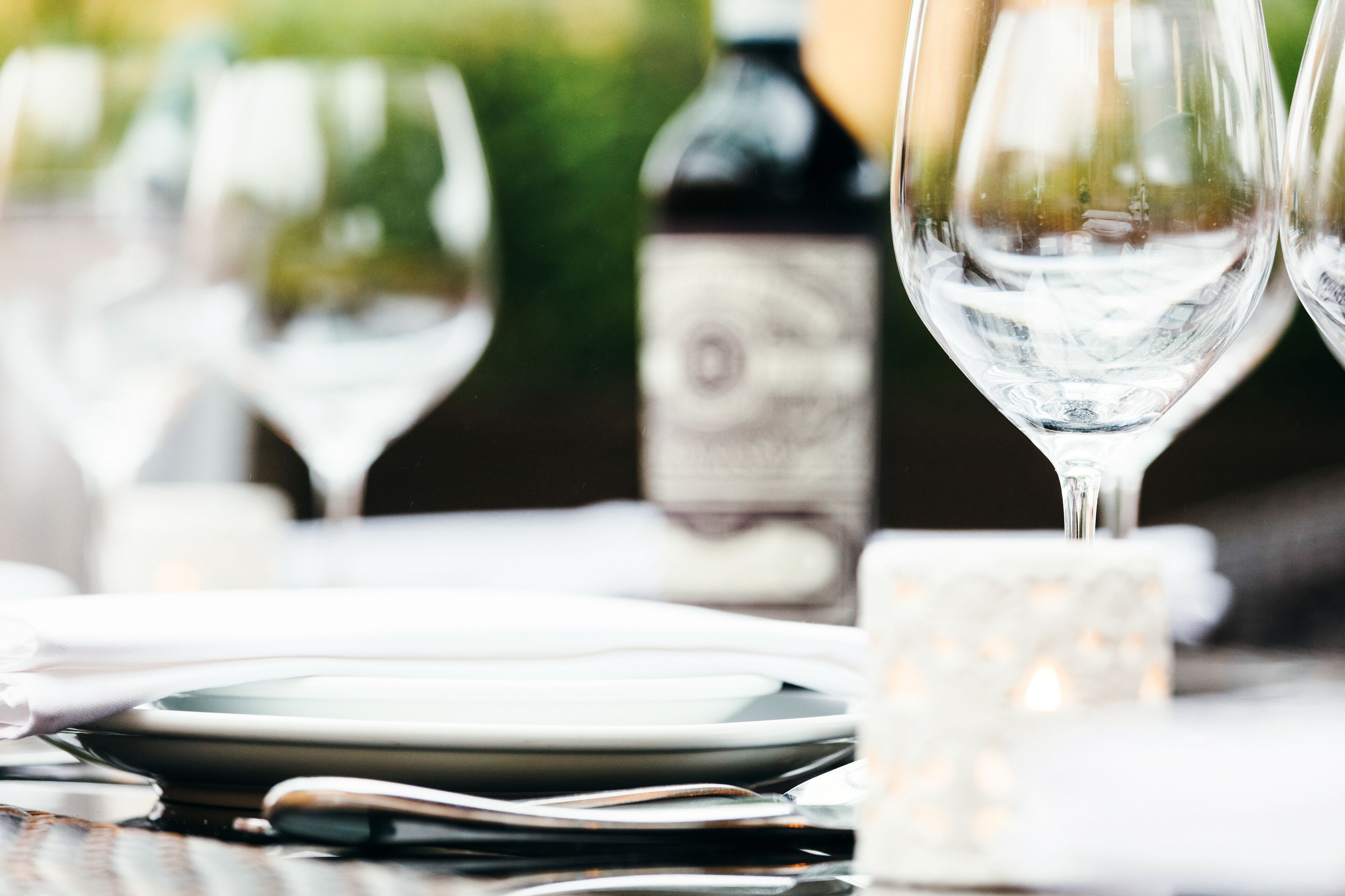 Une table à manger avec des verres à vin, des assiettes et une bouteille de vin.