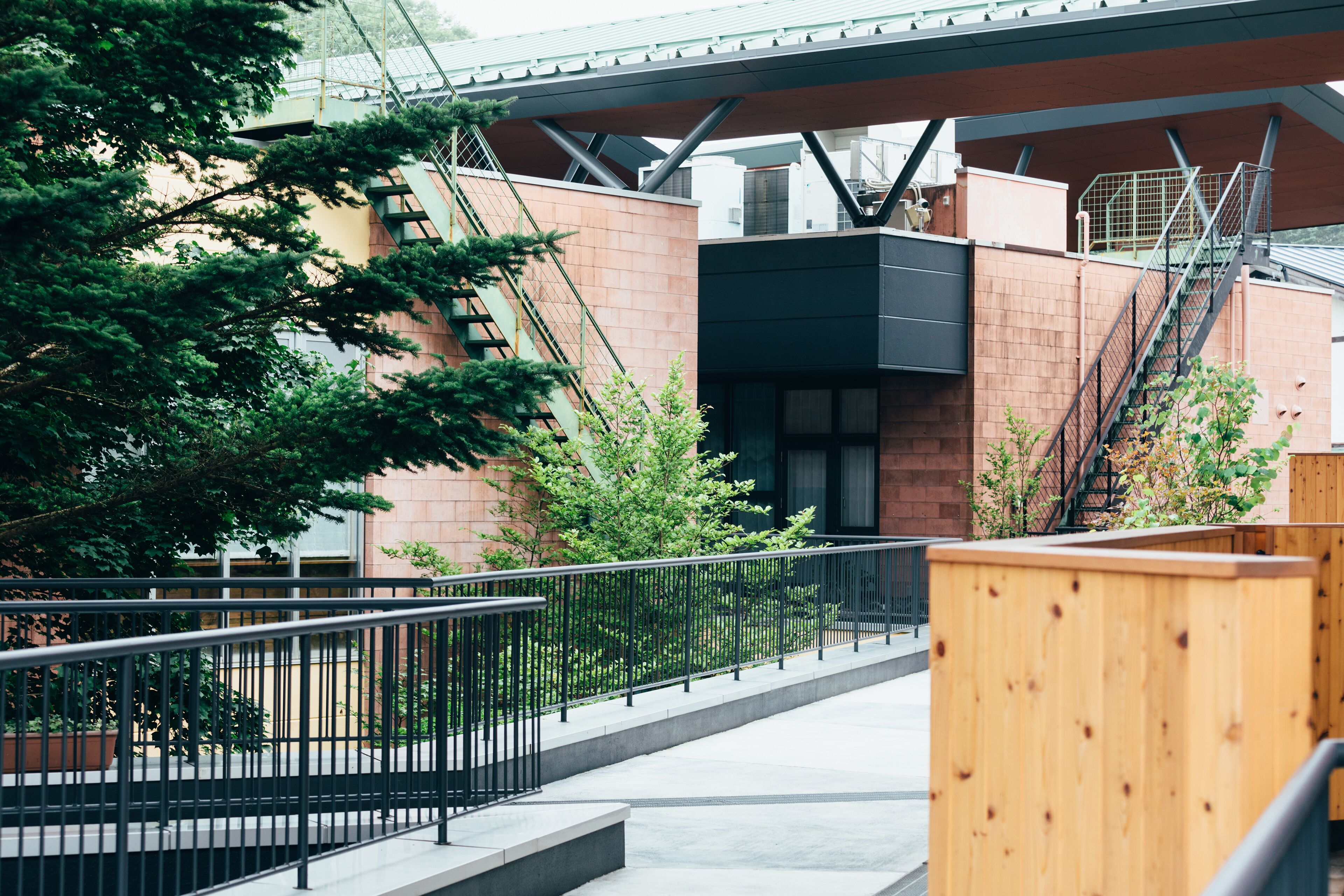 A modern building with a staircase, a wooden bench, and a metal railing.