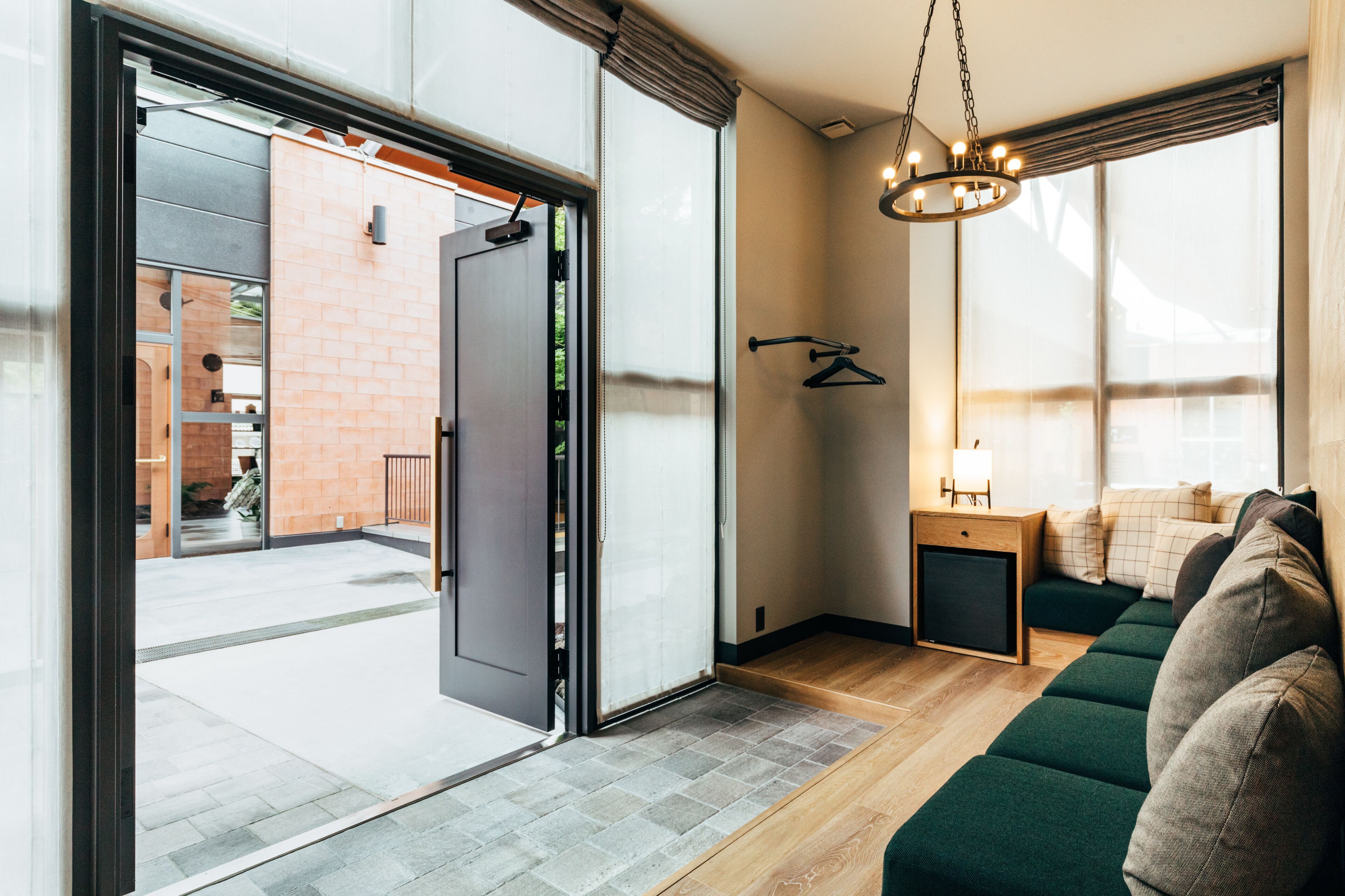 Ein modernes Interieur mit einer Schiebetür zu einem Außenbereich, ein gemütliches grünes Sofa und ein kleiner Holztisch mit einer Lampe.