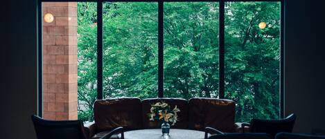 Una habitación con un ventanal grande, una mesa redonda y un sofá con un jarrón de flores.