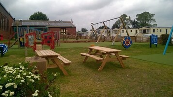 A playground with swings, climbing structures, and picnic tables.