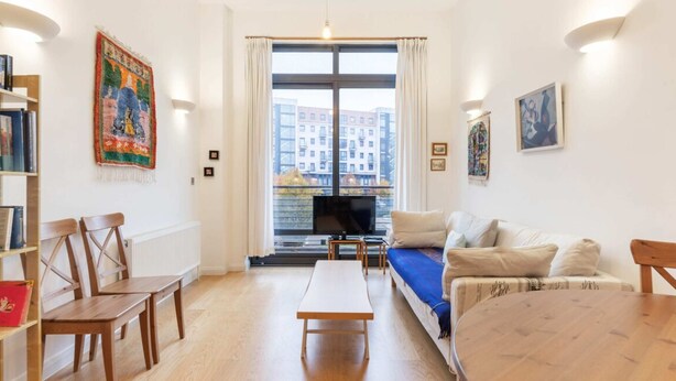 A living room with a sofa, a TV, a wooden table, and a bookshelf. - Beautiful 1 Bedroom Apartment in Shepherd's Bush (London)