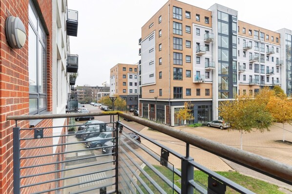 A modern apartment building with multiple floors, balconies, and a parking area visible below.