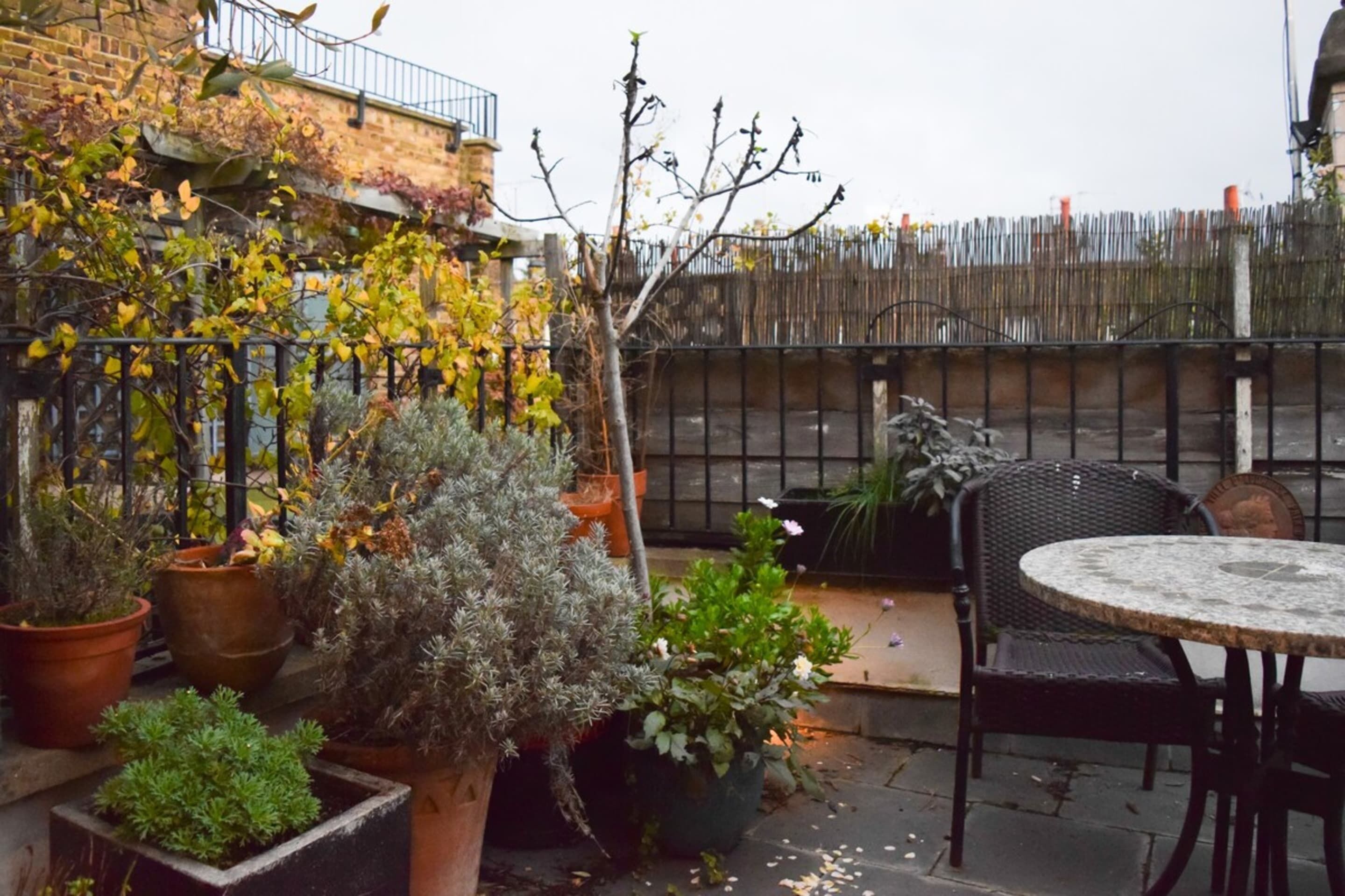 An outdoor patio with potted plants, a round table, and chairs.