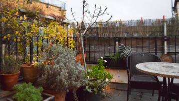 An outdoor patio with potted plants, a round table, and chairs.