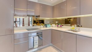 Une cuisine moderne dotée d’appareils électroménagers en acier inoxydable, d’un grand îlot central et d’un pare-feu en miroir.