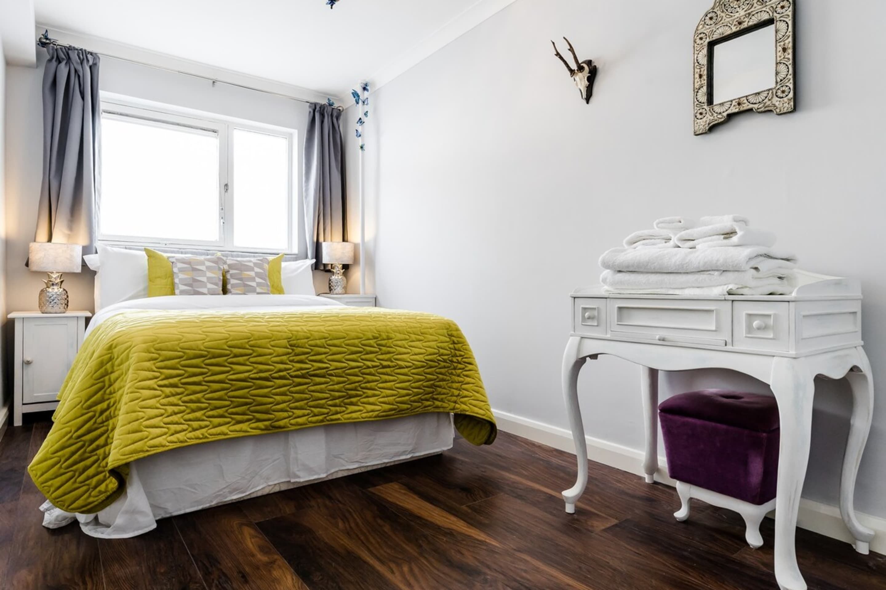 A bedroom with a bed, a nightstand, a dresser, and a window with curtains.