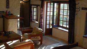 A room with a bed, a wooden table, and a chair. There are windows with curtains, a ceiling fan, and a wall-mounted shelf. - Peaceful Detached Cottage Studio French Countryside Private Garden Nature Lovers (champagne mouton)