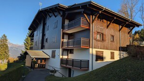 A multi-story chalet with balconies, a ski lift, and a mountain backdrop. - Apartment Combloux sleeps 4 at the foot of the slopes (Combloux)