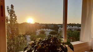 A kitchen with a large window overlooking a residential area during sunset. - PENTHOUSE APARTMENT CALA ANGUILA BALCONY (Cala Anguila)