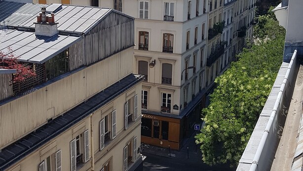 A street view with buildings, a crosswalk, and a parked car. - Hotel Cosmos (Paris)