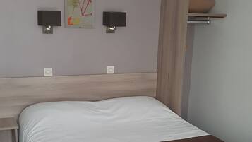 Quarto com cama, escrivaninha e duas luminárias de parede.