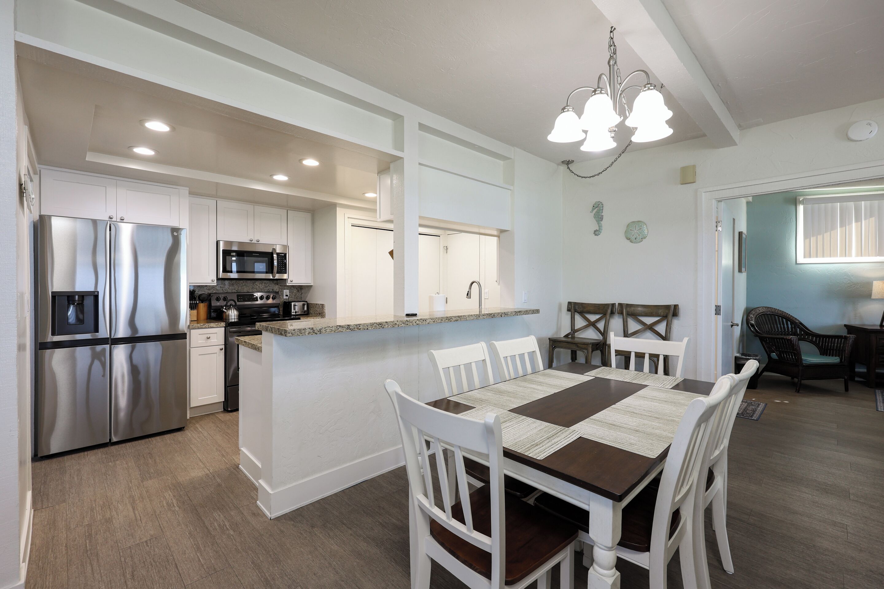 A modern kitchen with white cabinetry, stainless steel appliances, and a central island with seating.