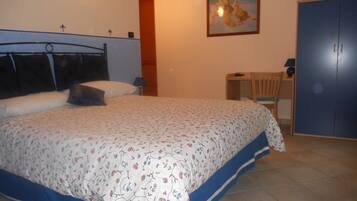 Un dormitorio con cama, escritorio, silla, armario y un cuadro en la pared.