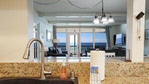 A kitchen with a granite countertop, a sink, a soap dispenser, and a paper towel holder.
