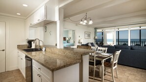Una cocina moderna con encimeras de granito, armarios blancos y una zona de comedor con mesa y sillas.
