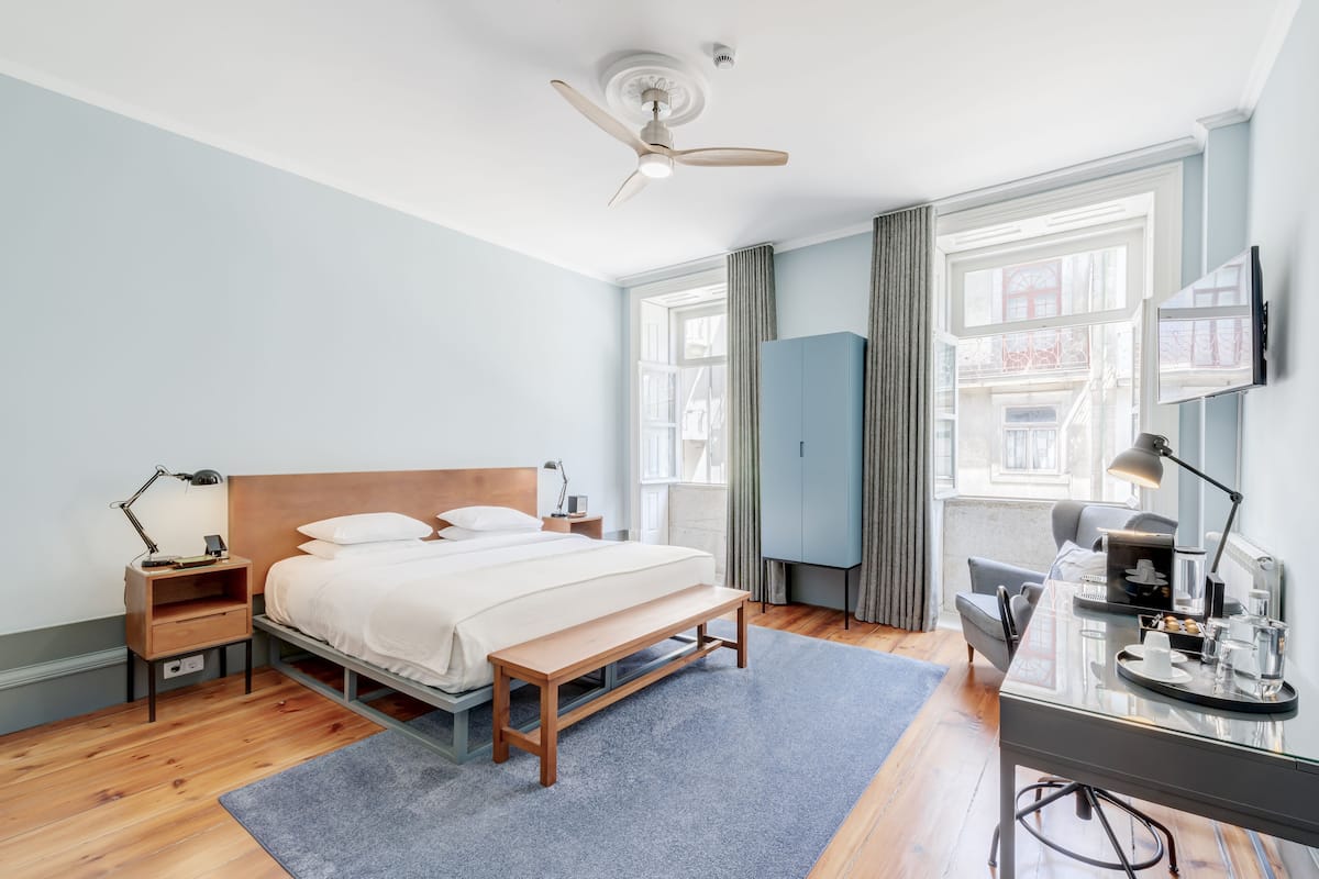 Un dormitorio moderno con cama, mesitas de noche, escritorio y ventilador de techo.