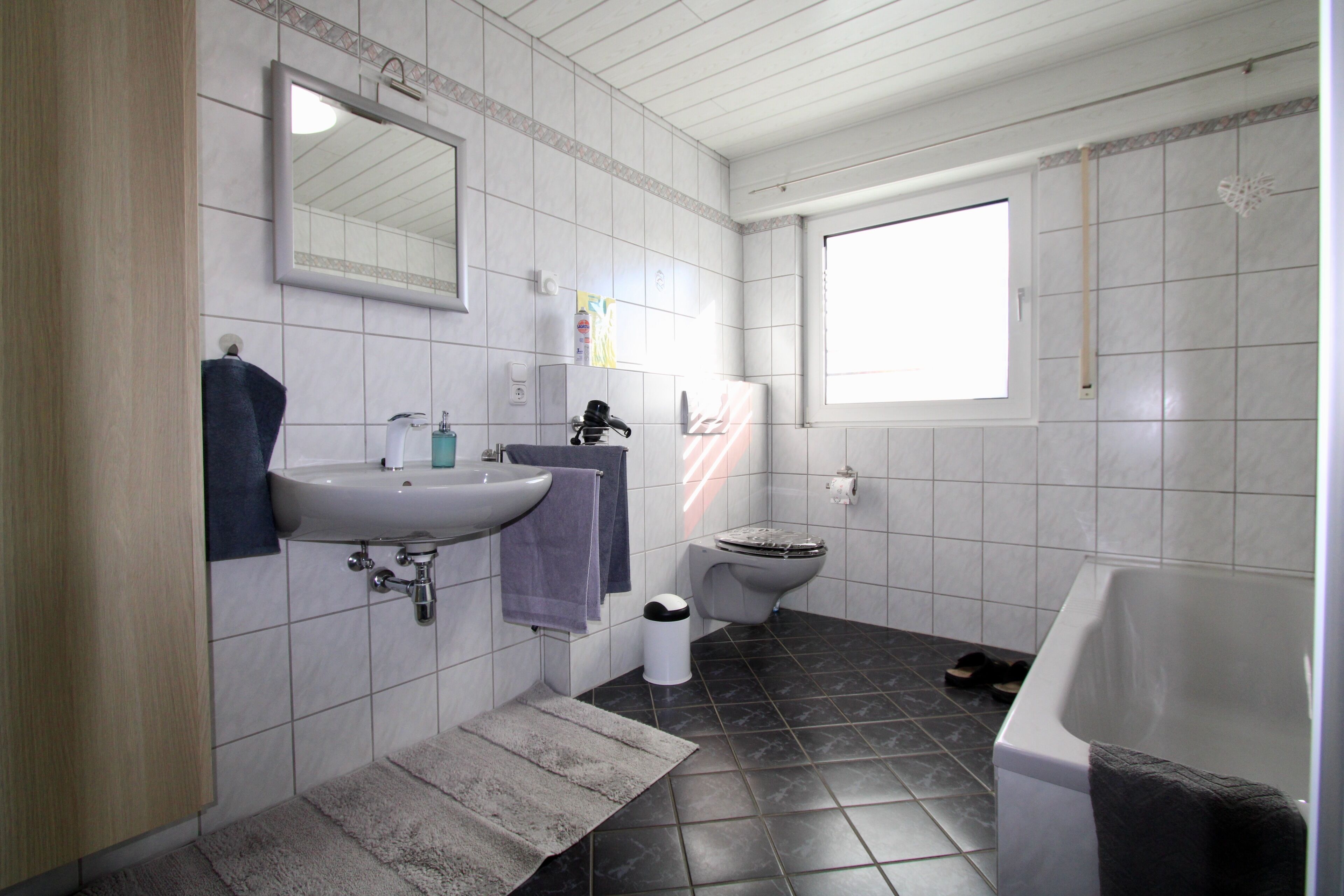A bathroom with a sink, mirror, toilet, and bathtub.