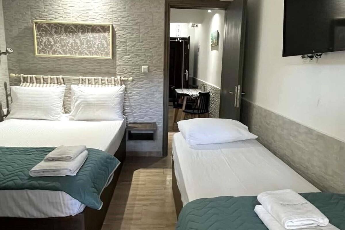 A hotel room with two beds, a TV, a mirror, and a small table.
