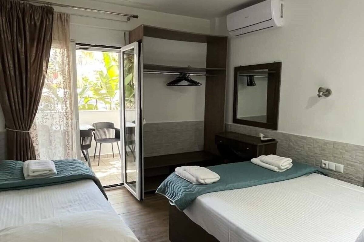 A hotel room with two beds, a bathroom, and a sliding glass door leading to an outdoor area.