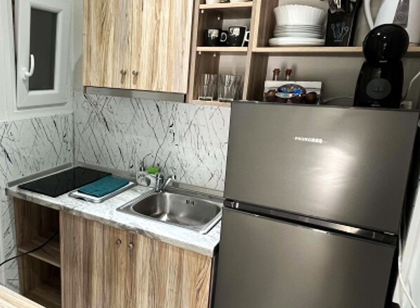Una cocina con refrigerador de acero inoxidable, un lavamanos, armarios de madera y un salpicadero de mármol.