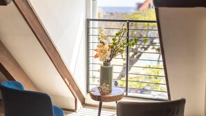 Una habitación con tragaluz, una pequeña mesa con un florero y una silla azul.