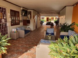 A spacious indoor area with a tiled floor, wicker furniture, and potted plants.