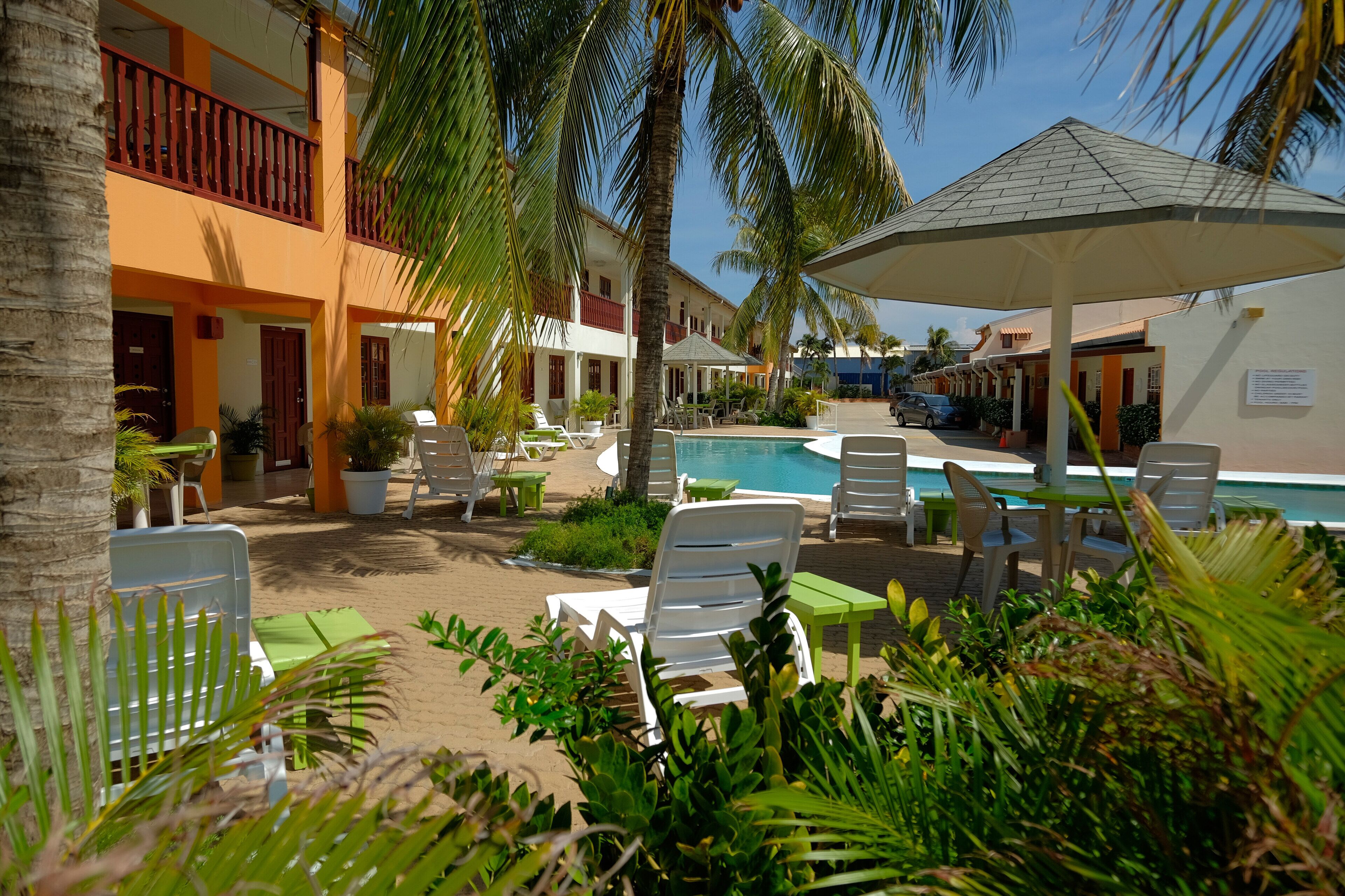 A poolside area with lounge chairs, a pool, and a covered seating area.