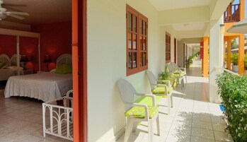 A hotel corridor with a bed, chairs, and a window.