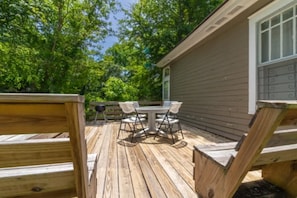 Enjoy outdoor dining or socializing on the deck with a round table and four chairs amidst lush greenery.